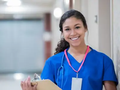 A medical student smiling, holding chart