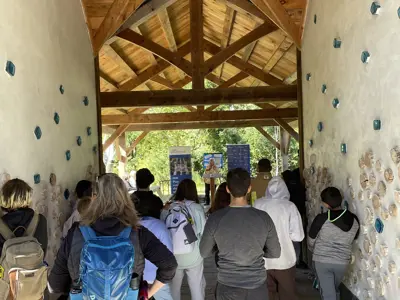 A group listens to opening remarks under the Ecology Park pavilion