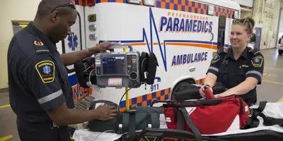 Two paramedics standing next to an ambulance