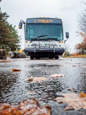 A bus departs a sheltered transit stop at Fleming College